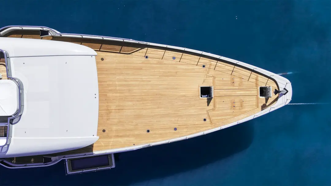 Aerial top-down view of a teak foredeck and bow cutting through deep blue water