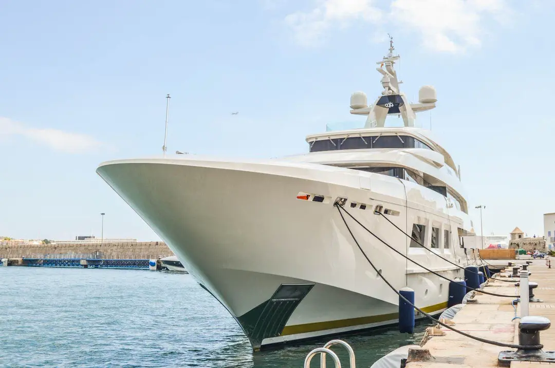 Superyacht moored bow-on to a stone harbor quay with lines led ashore