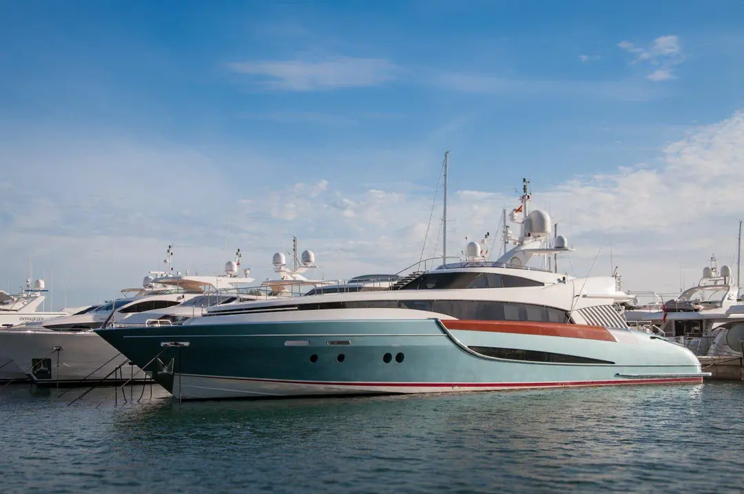 Line of superyachts berthed side by side in a marina under a clear blue sky