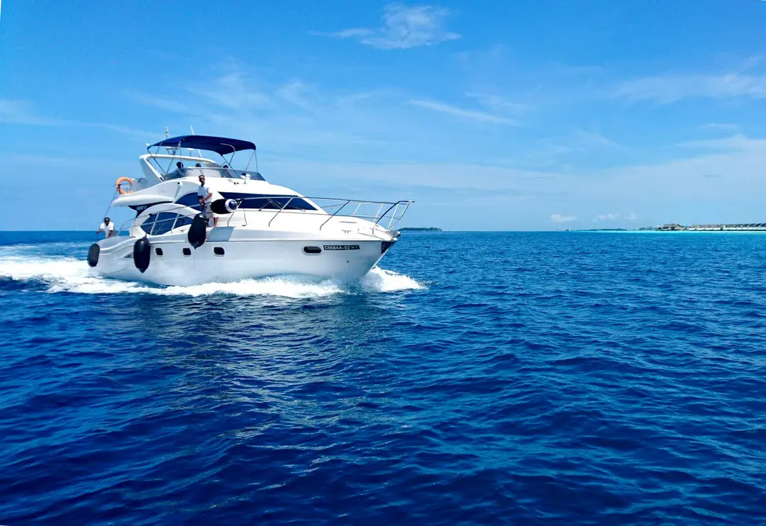 Flybridge motor yacht cruising at speed across open tropical water
